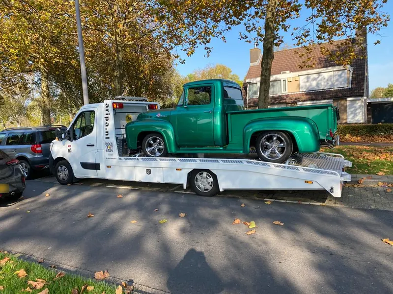 Groene klassieke Ford pick-up op het laadplatform van een Aripa autotransporter